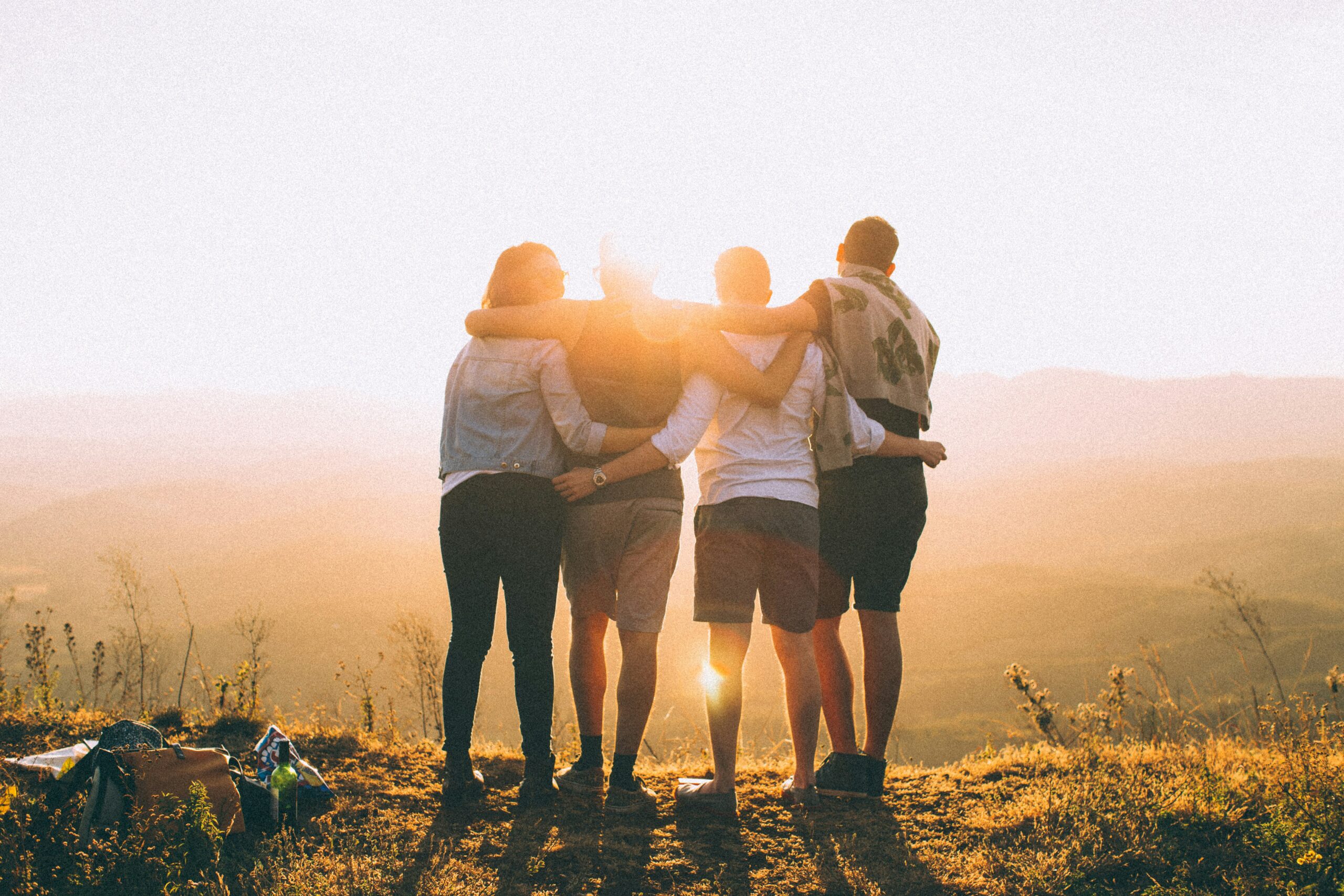 Grupo se abraçando ao pôr do sol